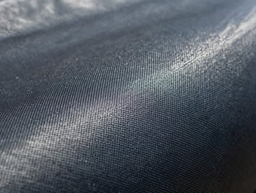 Extreme macro shot of UV-stabilized agricultural ground cover fabric, highlighting the tight fiber density and puncture-resistant weave under direct daylight.