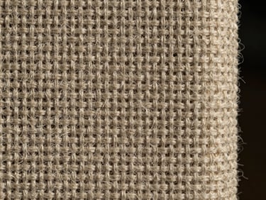 Extreme close-up detail shot of a thick nonwoven geotextile fabric, showcasing the dense, interlocking fiber matrix under sharp side-lighting, kissing the right edge of the frame