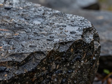 Textura de piedra húmeda y oscura con gotas de lluvia cayendo, primer plano macro, luz natural difusa de un día nublado.