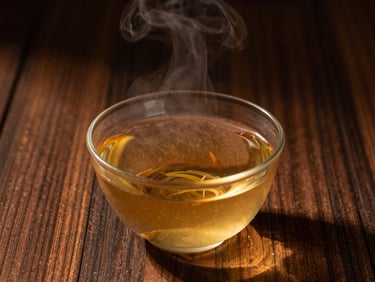 Warm golden light catching the steam rising from a bowl of herbal-infused water, rich dark wooden background, soft shadows, 35mm