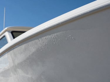 Extreme close-up of water beading perfectly on a freshly ceramic-coated boat hull, reflecting crisp blue sky, sharp focus