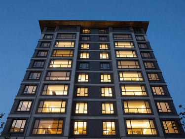 Wide-angle exterior shot of a completed luxury residential building facade at twilight, deep blue sky, warm interior lights reflecting on raw concrete and glass, low-angle perspective.