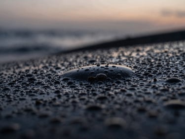 Extreme macro close-up of textured liquid surfaces with light refracting through glass, low-contrast, diffused twilight color palette