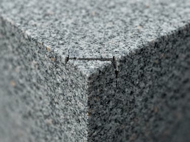 Extreme close-up macro shot of a waterjet-cut granite edge, cross-section revealing clean stone separation with zero chipping or micro-cracks, overcast north-facing light, cool grey and black granite grain visible in sharp relief