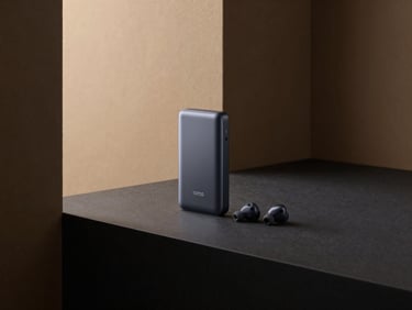 Minimalist product photography of a sleek, branded power bank and wireless earbuds on a dark, high-contrast surface, architectural lighting.