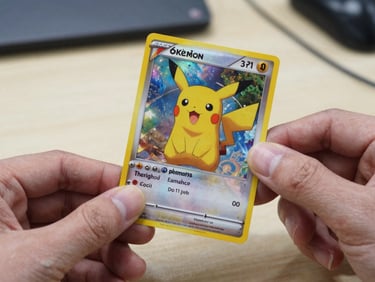 Close-up of a Pokémon trading card held between two fingers, the holographic foil catching honest indoor light, card art clearly visible, plain table surface in background, no soft filters