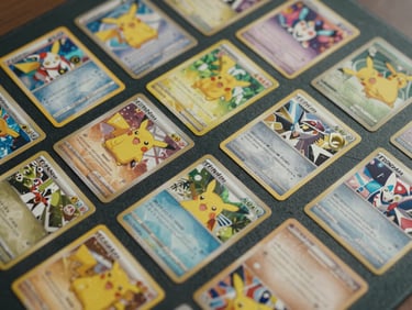 Overhead close-up of Pokémon trading cards spread flat on a dark mat, vibrant card artwork visible, honest indoor light, no hands, cards slightly overlapping