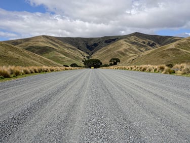 A clean gravel pad on a working sheep station in Canterbury, wide environmental shot with rolling hills under an overcast sky.