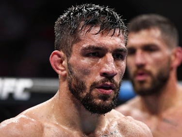 Close framing on a UFC fighter's focused face under octagon ring lighting, sweat visible, opponent blurred behind, high-contrast dramatic light
