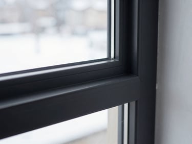 Close-up architectural shot of a minimalist black aluminium window frame profile, clean lines, sharp shadows, 35mm