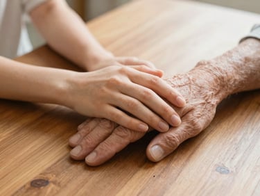 Close-up of a daughter's hand reassuringly placed over her elderly father's hand at a wooden table, warm natural light, 35mm