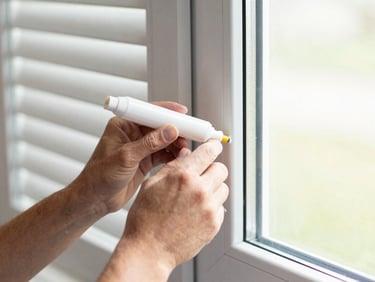Close-up of a technician's hands applying sealant around a window frame for improved insulation, clean tools, natural daylight, crisp details, 35mm.