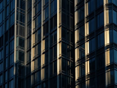 Close-up of modern corporate skyscraper facade, sharp architectural shadows, cool-toned daylight with warm gold reflections on glass and steel, 35mm