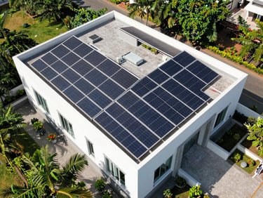 Wide aerial drone shot of a modern Hyderabad villa rooftop covered in perfectly aligned solar panels under bright Indian sunlight.