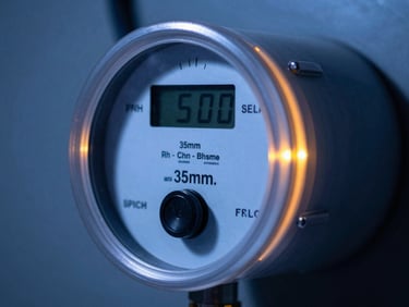 Close-up of an industrial energy meter with retrofitted digital transmitter, glowing amber accents, high-contrast technical lighting, macro lens, detailed hardware, 35mm