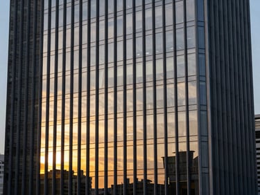 High-rise corporate headquarters building with glass facade, reflection of golden hour sunset, architectural photography.