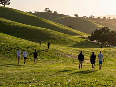 Wide shot of the Azusa foothills with players walking on the green during golden hour, long shadows.