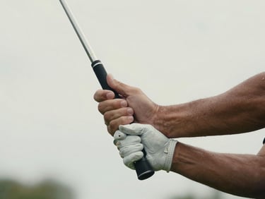 Close-up shot of hands guiding a golf club swing under soft daylight, focus on the grip and motion.