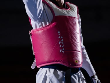 Close-up of taekwondo chest protector and blue belt, dramatic key lighting, high contrast, dark athletic mood