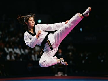 Dynamic low angle shot of a taekwondo athlete executing a high kick mid-air, dramatic high-contrast key lighting, deep shadows and sharp fuchsia highlights, 35mm