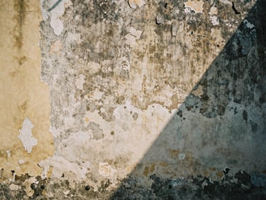 Close-up of a weathered, textured wall with peeling paint in a Vietnamese alley, harsh midday shadows, natural ambient light, muted realistic tones, high contrast, 35mm film grain, quiet candid composition.