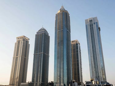 Sleek high-rise luxury residential towers in Dubai Marina, modern architecture, bright daylight, clear sky.