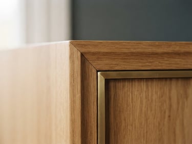 Straight-on macro architectural shot of a perfectly joined solid oak and brushed brass cabinet corner, soft diffused window light, shallow depth of field, 35mm