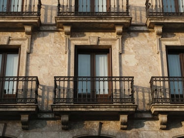 Close-up of a classic Madrid apartment facade, elegant wrought-iron balcony with warm afternoon light reflecting on stone, straight-on framing.