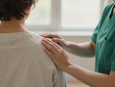 Reassuring hands-on-shoulder interaction between a nurse and a recovering patient, shallow depth of field
