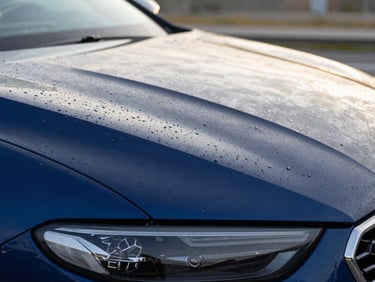 Crisp shot of water droplets rolling off a freshly waxed deep blue car hood, natural golden hour light, macro lens detail, 35mm lens
