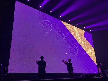 Low-angle shot of professional technicians setting up a massive LED video wall on a stage, purple backlighting, cinematic haze, high contrast