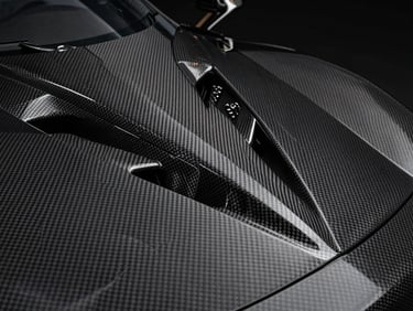 Carbon fiber weave detail of a modern supercar side intake, sharp geometric lines, low-key studio lighting