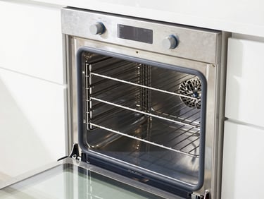 bright clean commercial photography, high-key natural daylight, close-up of a gleaming stainless steel oven interior with spotless racks, sharp focus, 35mm