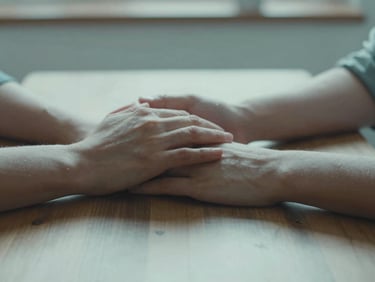 Close-up of two hands gently resting near each other on a wooden table, soft diffused morning light, shallow depth of field, muted teal tones, 35mm photography.