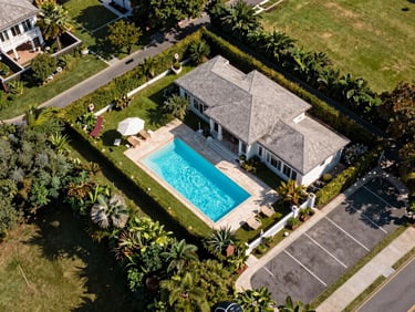 Overhead plot overview of Royal Pool Villa — looking down at the 3228 sq.ft parcel from an elevated vantage point, pool rectangle visible, garden strip, bungalow footprint, and parking bay all within the perimeter, midday light