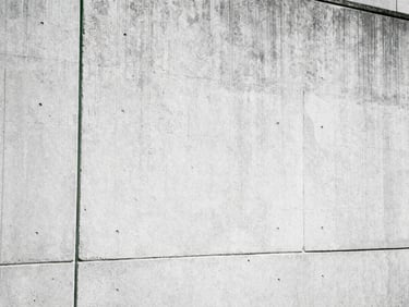 Grainy urban texture of concrete walls under harsh midday sun, Dutch angle, raw film aesthetic.