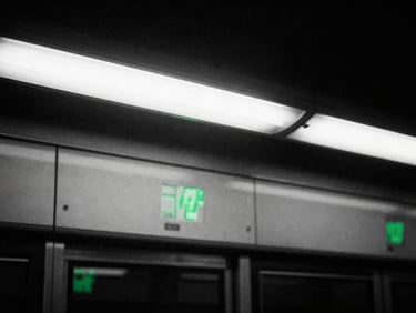 Gritty high-contrast monochrome close-up of a subway platform under harsh fluorescent light, raw 35mm film grain, green reflections