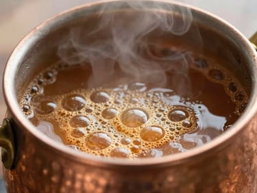 Close-up of bubbling golden caramel inside a traditional hammered copper kettle, warm steam, soft natural light, 35mm