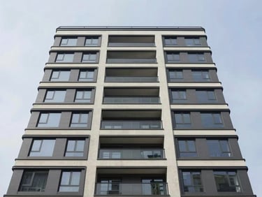 Architectural exterior facade of a modern residential building in daylight, clean concrete and glass surfaces, symmetrical composition, overcast neutral sky, no people, wide environmental framing