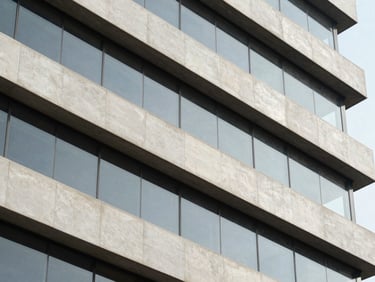 Close architectural detail of a completed commercial office building facade in Lima Miraflores, north-facing daylight on glass and concrete panels, clean geometric lines, no people