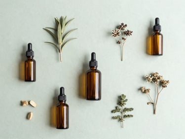 Minimalist flat-lay of raw botanical ingredients and clean amber glass bottles on a light sage green surface, soft natural overcast daylight