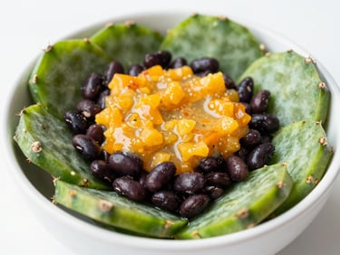 Close-up of a vibrant cactus bowl with green nopales, black beans, and orange citrus dressing in bright daylight.