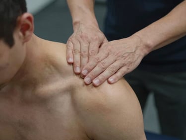 Close-up of hands-on manual physical therapy, a therapist performing precise tissue mobilization on an athlete's shoulder, dark clinical setting