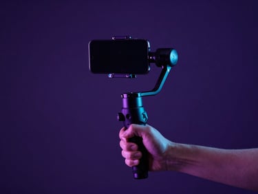 Dynamic behind-the-scenes shot of a creator holding a gimbal stabilizer with a smartphone under dramatic purple and cyan neon gel lighting