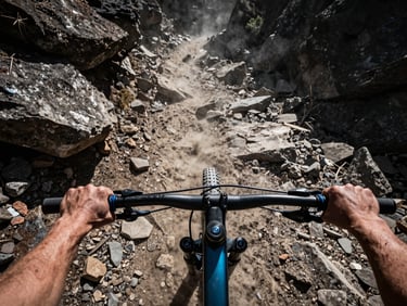First-person POV of hands on mountain bike handlebars descending a rocky singletrack, direct harsh sunlight, dust in the air
