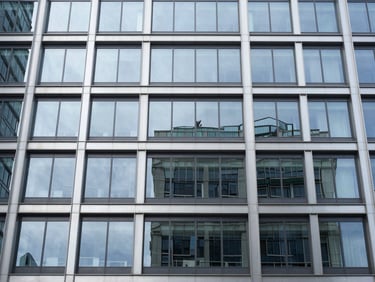 Straight-on architectural elevation, cool metallic tones, a modern 12-story commercial building envelope with structural glazing, high-contrast reflections on glass panels.