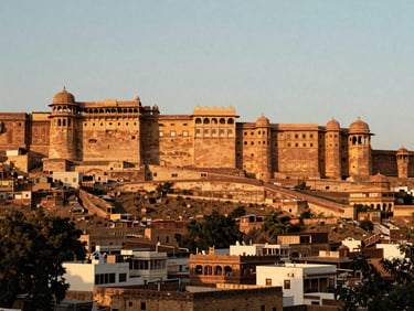 A majestic Rajasthani sandstone fort overlooking an ancient city at sunset, warm golden light, medium format film style.