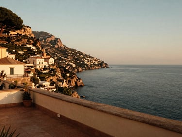 A luxurious cliffside terrace overlooking the deep blue Mediterranean sea in Amalfi, warm golden hour glow.