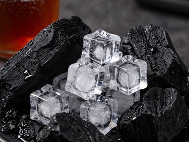 Clean, clear ice cubes piled next to natural charcoal chunks, dramatic side lighting, high texture detail