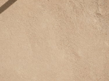 Extreme close-up of sustainable rammed earth wall texture, tactile details, warm architectural neutral colors, soft natural lighting.
